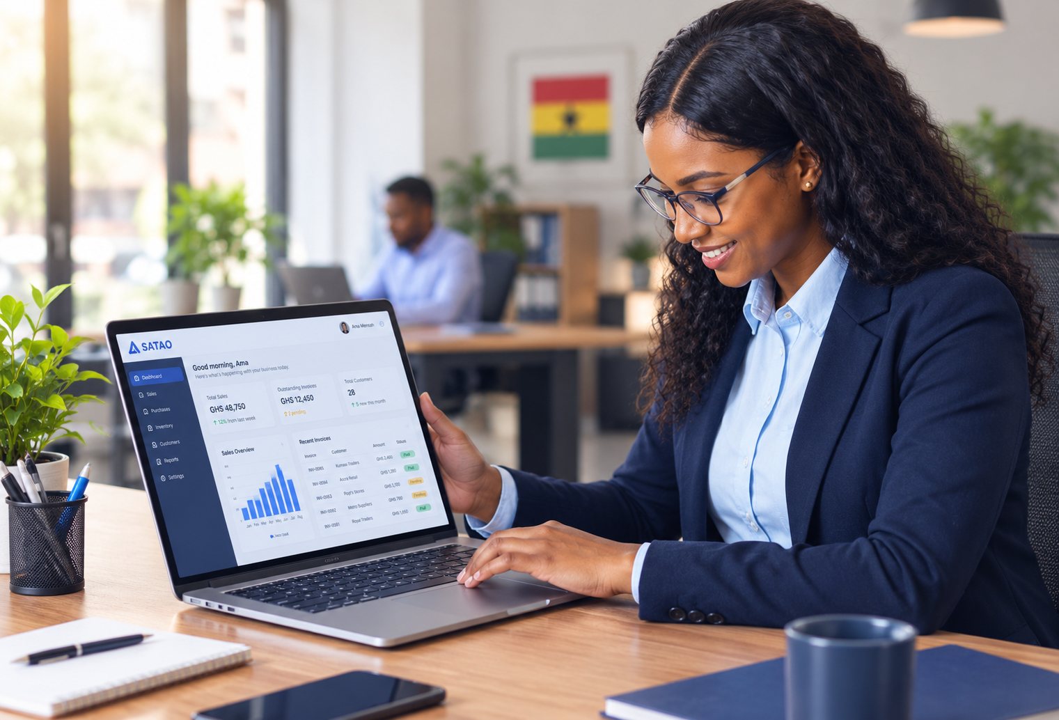 A business owner smiling while reviewing her SATAO dashboard on a laptop — sales, outstanding invoices, and customer totals at a glance.